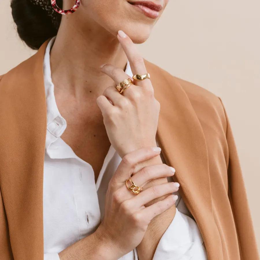 Woman wearing several stacked adjustable gold Caracol rings on one hand