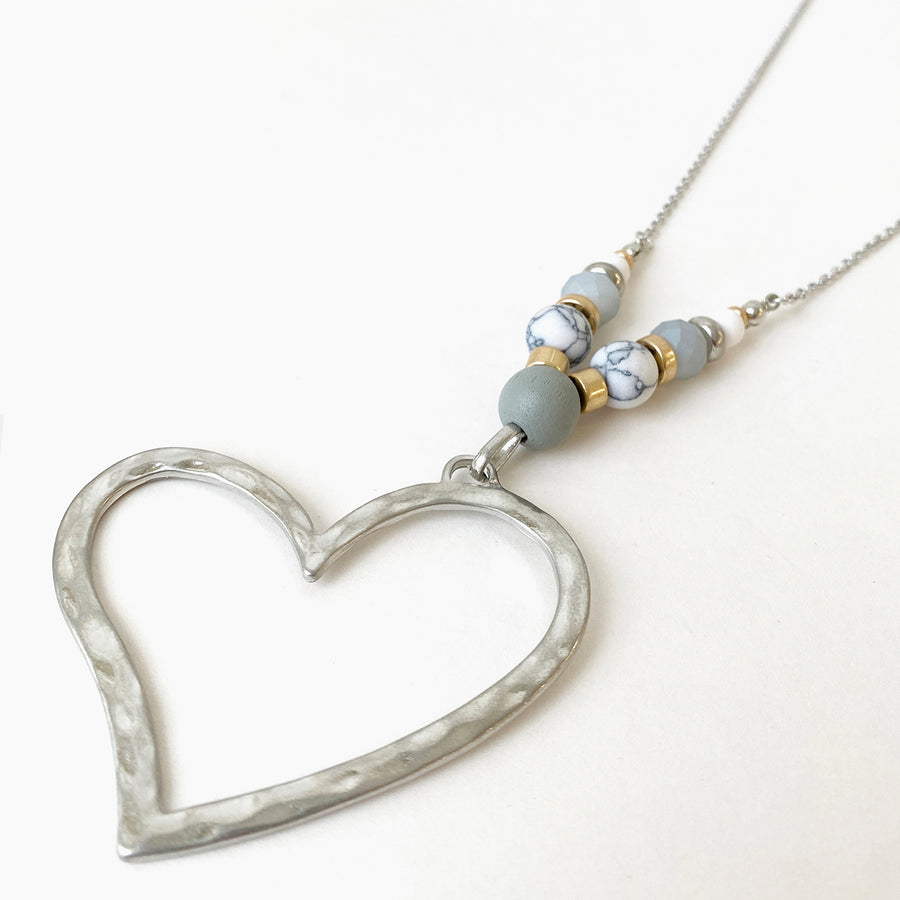 LONGUE CHAÎNE AJUST. AVEC GROS PENDENTIF C?UR DE MÉTAL MARTELLÉ ET BILLES ASSORTIES - BLANC ET ARGENT | LONG ADJ. CHAIN WITH BIG HAMMERED METAL HEART PENDANT WITH ASSORTED BEADS - WHITE & SILVER